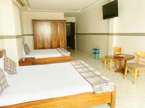 a room with two beds and a table and a tv at Khách sạn Hoàng Hải in Ho Chi Minh City