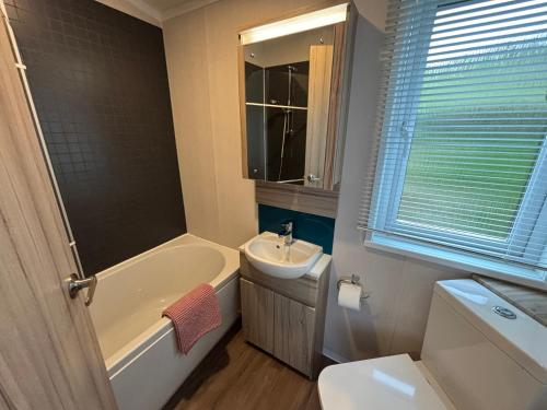 a bathroom with a tub and a sink and a toilet at The Lodge at Pennant-Igyn in Pwllheli