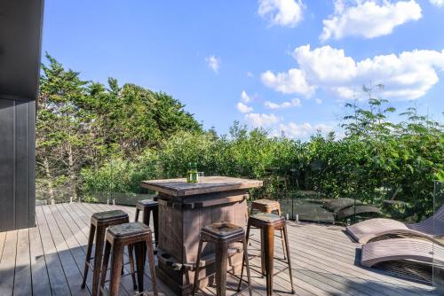 a patio with a bar and stools on a deck at The Coastal Nest - Waitarere Beach Holiday Home in Levin