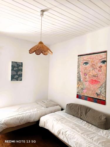 deux lits dans une chambre avec un tableau au mur dans l'établissement Le Jardin des Muses, à Jard-sur-Mer