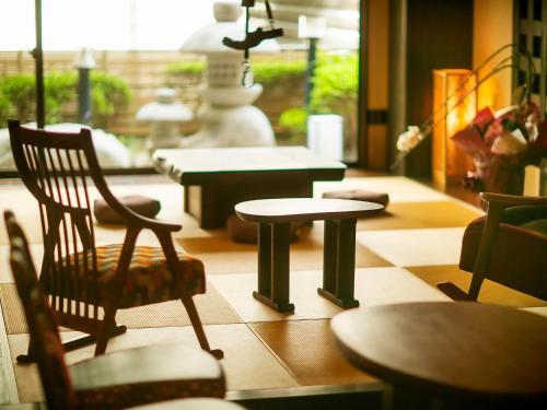 a room with a chair and tables and a statue at Yuhigauraonsen ShizukaHanaogi in Kyotango
