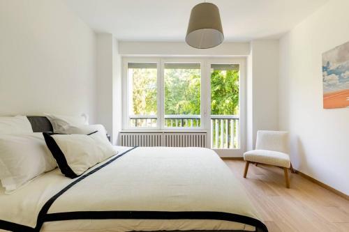 a white bedroom with a bed and a window at Luxurious 2BR Family Apartment - Champel in Geneva