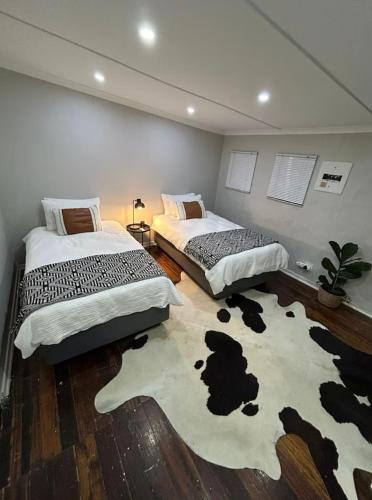two beds in a room with a cow rug at Prime Location Kimberley 3 in Kimberley
