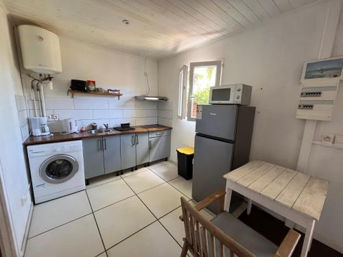 a small kitchen with a refrigerator and a table at Ti Kaz avec SPA, proche du lagon in Saint-Gilles les Bains