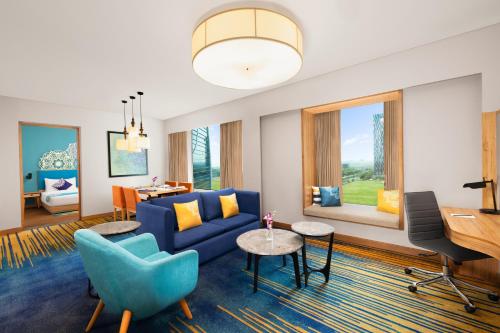 a living room with a blue couch and a desk at Grand Mercure Ahmedabad GIFT City - An Accor Hotels Brand in Gandhinagar