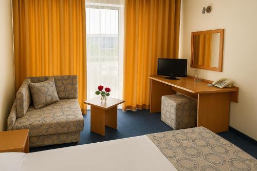 a hotel room with a bed and a desk and a chair at Hotel Perunika in Golden Sands