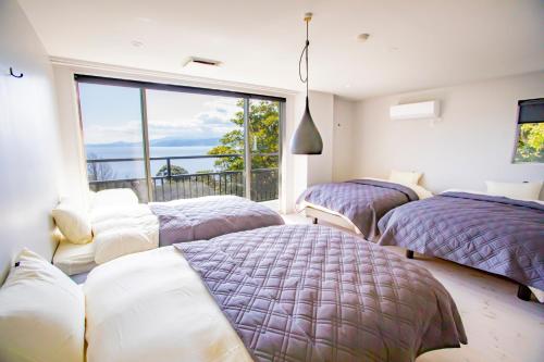 3 posti letto in una stanza con una grande finestra di 真鶴ペットと泊まれて専用屋上付きスタイリッシュなapartmentHotel途乃中RC2 a Manazuru