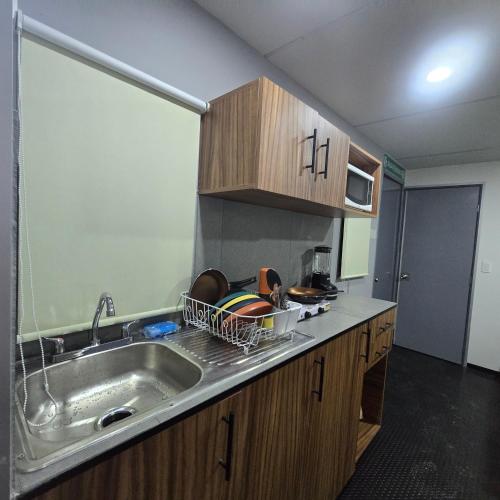 a kitchen with a sink and wooden cabinets at Casa en movimiento playabonita in Campeche