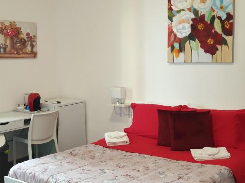 a bedroom with a red bed with a desk and a table at Cartia Affittacamere in Ragusa
