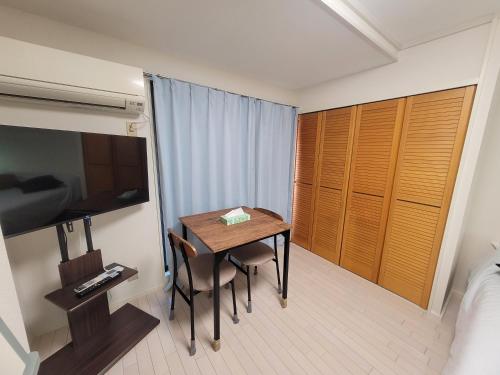 a small room with a table and a bedroom at Liberty Shinjuku House in Tokyo