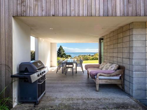 a patio with a grill and a table and chairs at Ligar Escape - Golden Bay Holiday Home in Tarakohe