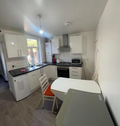 a kitchen with white cabinets and a table and chairs at The Ardens in Gillingham