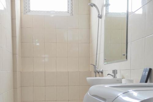 a white bathroom with a sink and a mirror at Spacious 2BR at Vida View Makassar Apartment By Travelio in Pampang