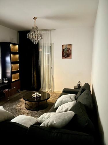 a living room with two black couches and a chandelier at Comfortable Apartment Bedroom And Spacious Living Room Family and Couple in Sharjah