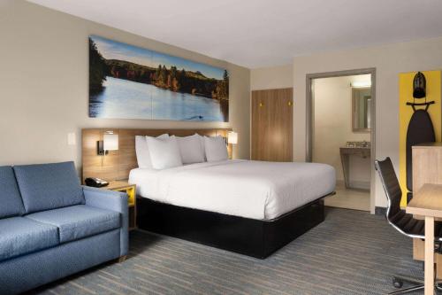 a hotel room with a bed and a blue couch at Days Inn by Wyndham Weldon Roanoke Rapids in Weldon
