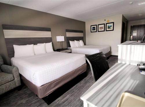 a hotel room with two beds and a desk at Baymont by Wyndham Lafayette - Purdue University in Lafayette