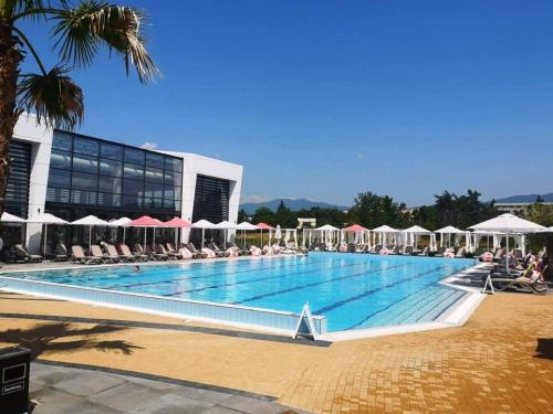 a large swimming pool with chairs and umbrellas at Харизма in Hisarya