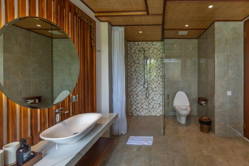 a bathroom with a sink and a toilet and a mirror at Micaela Bali Ubud Villas in Tegalalang