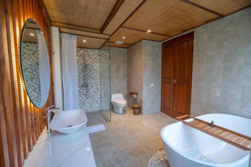 a bathroom with a tub and a sink and a toilet at Micaela Bali Ubud Villas in Tegalalang