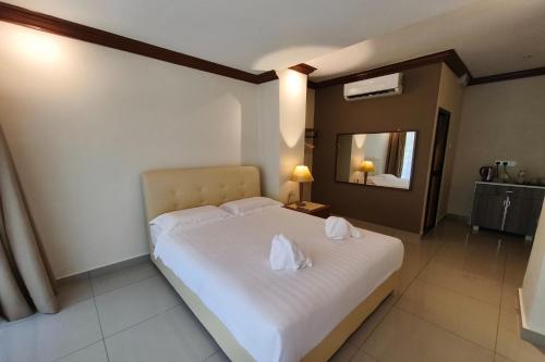 a bedroom with a white bed with two towels on it at AlSafina Forest Stay in Kemaman