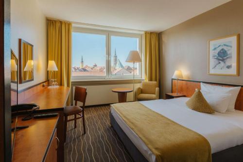 a hotel room with a bed and a desk and a window at Best Western Plus Hotel Bautzen in Bautzen