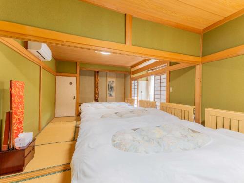 a room with two beds with green walls at 檜湯の宿　松伯 in Aoki-gemi