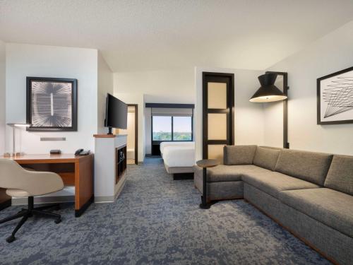 a hotel room with a couch and a desk and a bed at Hyatt Place Lakeland Center in Lakeland