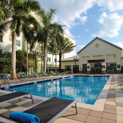 a large swimming pool with chairs and palm trees at Homewood Suites by Hilton Fort Lauderdale Airport-Cruise Port in Dania Beach
