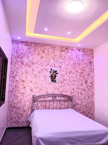 a bedroom with a pink wall with a bed at La Résidence du GABOU in Kédougou