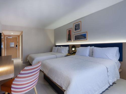 a hotel room with two beds and a table and chairs at Hampton by Hilton Saltillo Zona Aeropuerto in Saltillo