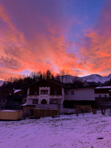 a sunset over a house in a snow covered yard at Martinshof Ladis in Ladis