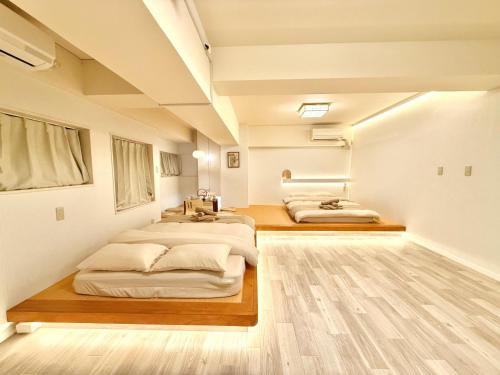 two beds in a room with white walls and wooden floors at 桜南大塚ハウス i in Tokyo