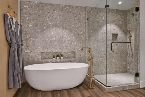 a bathroom with a white tub and a shower at Mission Pacific Beach Resort, part of JdV by Hyatt in Oceanside