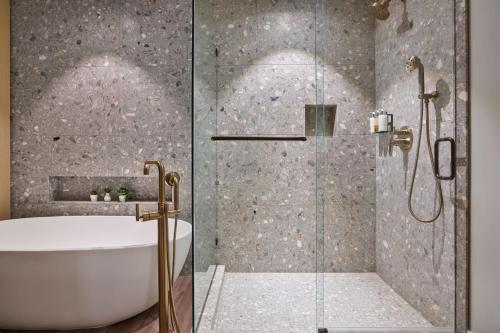 a bathroom with a shower with a tub and a sink at Mission Pacific Beach Resort, part of JdV by Hyatt in Oceanside