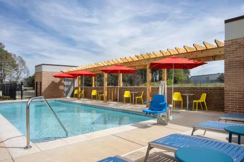 a swimming pool with chairs and umbrellas and a pool at Home2 Suites By Hilton Conyers Atlanta in Conyers
