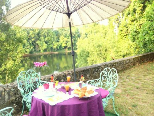 a table with a purple tablecloth and an umbrella at La Rebière d'Or, B&B et Gîte in Mouleydier