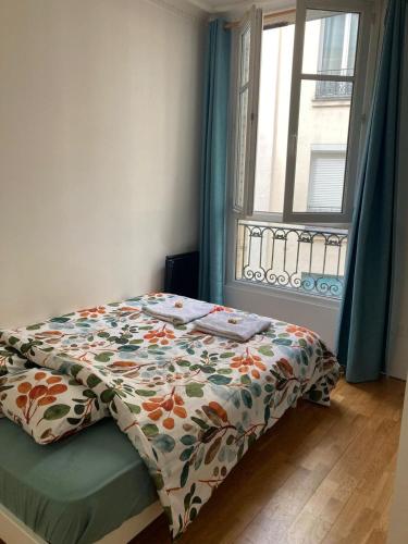 - une chambre avec un lit avec une couette à fleurs et une fenêtre dans l'établissement Charmant appartement parisien !, à Paris