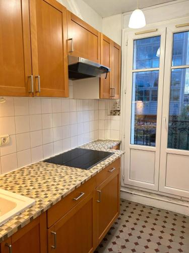 une cuisine avec des armoires en bois, un évier et une fenêtre dans l'établissement Charmant appartement parisien !, à Paris