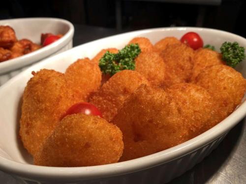 a white bowl filled with fried food with tomatoes and broccoli at Dormy Inn Premium Namba Natural Hot Spring in Osaka