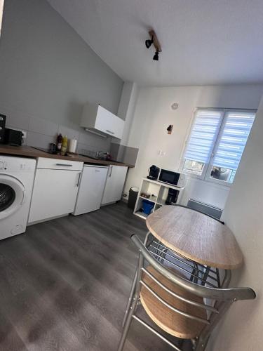 une cuisine avec une table et une cuisine avec des appareils électroménagers blancs dans l'établissement L'Alcove City Trip - 2 personnes - Centre ville, à Nancy