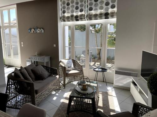 un salon avec un canapé, des chaises et une télévision dans l'établissement Charme et confort dans St Martin de Ré terrasse & parking, à Saint-Martin-de-Ré