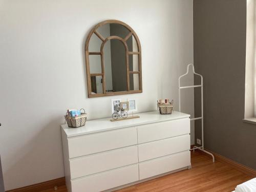 - une commode blanche avec un miroir au-dessus dans l'établissement Charme et confort dans St Martin de Ré terrasse & parking, à Saint-Martin-de-Ré