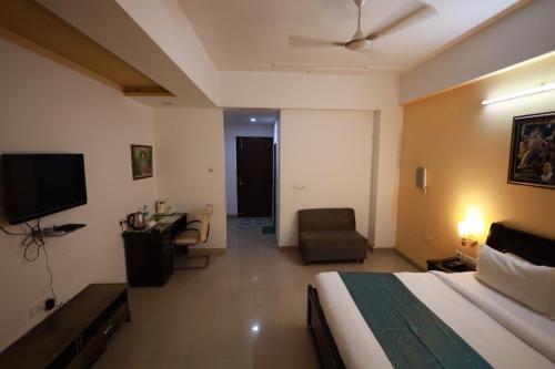 a bedroom with a bed and a chair and a television at Shanti Sewa Dham in Chhatikara