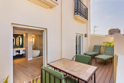 a balcony with a table and chairs and a bathroom at Melia Plaza Valencia in Valencia