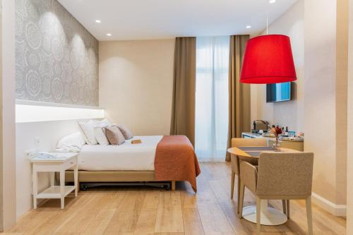 a bedroom with a bed and a desk and a red lamp at Melia Plaza Valencia in Valencia