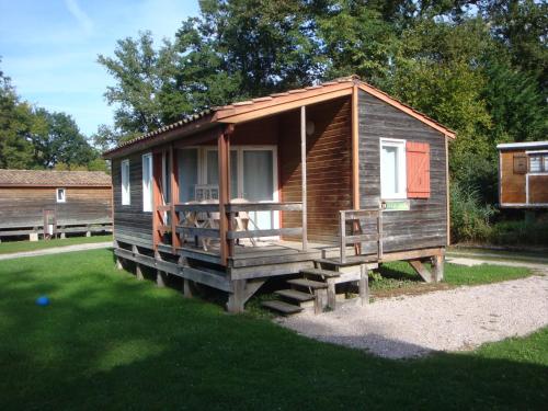 une cabane en bois avec une grande terrasse couverte sur l'herbe dans l'établissement La Pourvoirie des Ellandes, à Excenevex