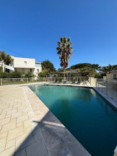 une piscine avec une clôture et un palmier dans l'établissement La Petra Marinella - Appt climatisé avec piscine, à LʼÎle-Rousse