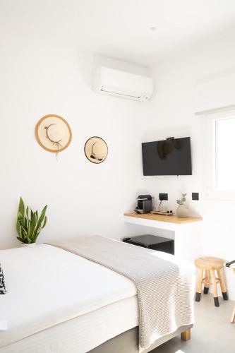 a white bedroom with a bed and a desk at Eleana Hotel in Tinos Town