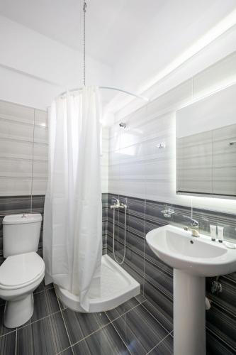 a white bathroom with a toilet and a sink at Aleksander ApartHotel in Ksamil
