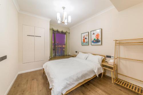 a white bedroom with a bed and a window at 重庆乐隐江景民宿 in Chongqing